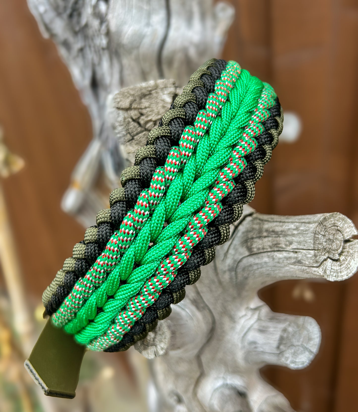 Green and black paracord dog collar on a tree stump the background is blurred