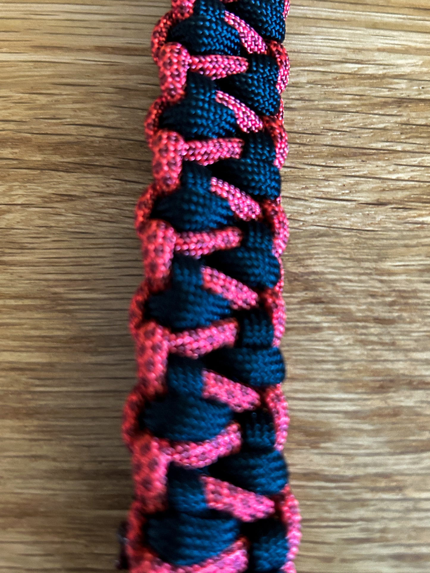 Pink and black braided cord on a wooden surface