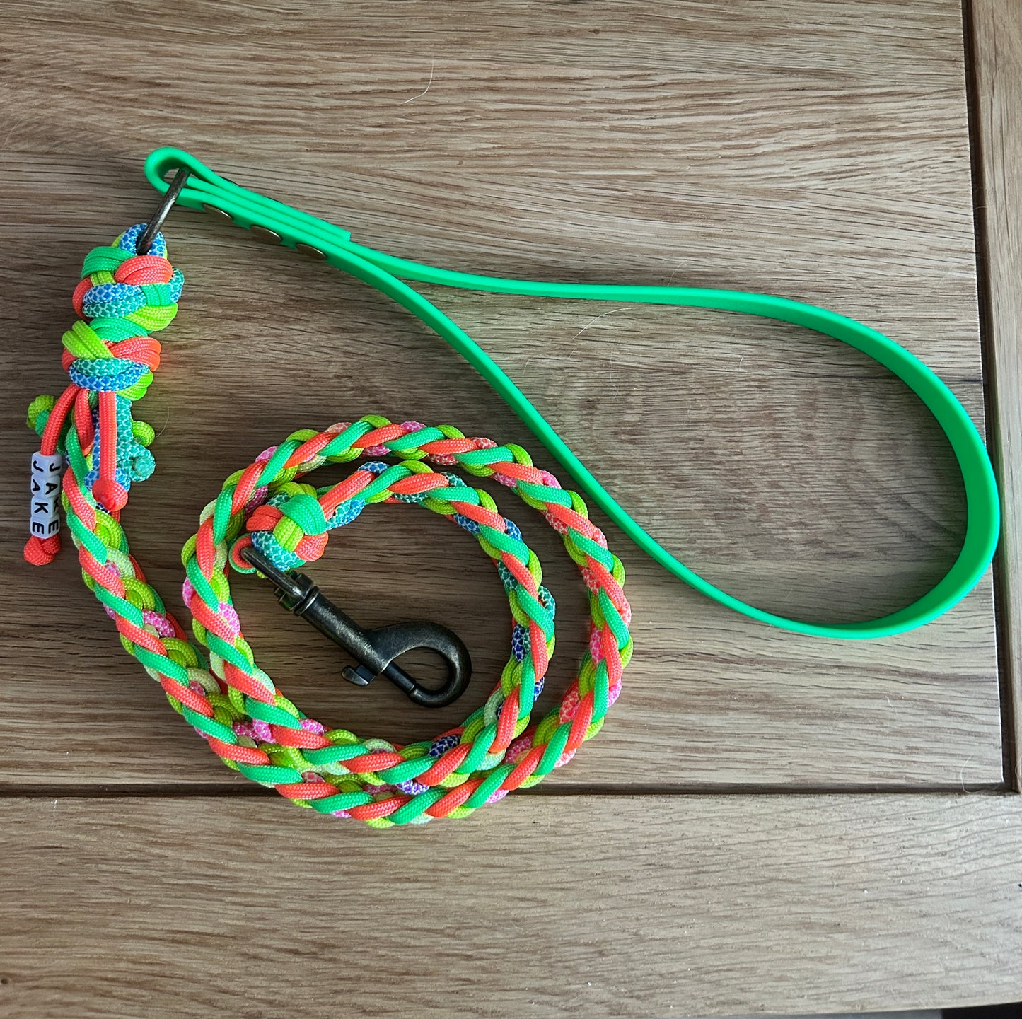 Colourful braided dog lead with Biothane handle on a wooden surface