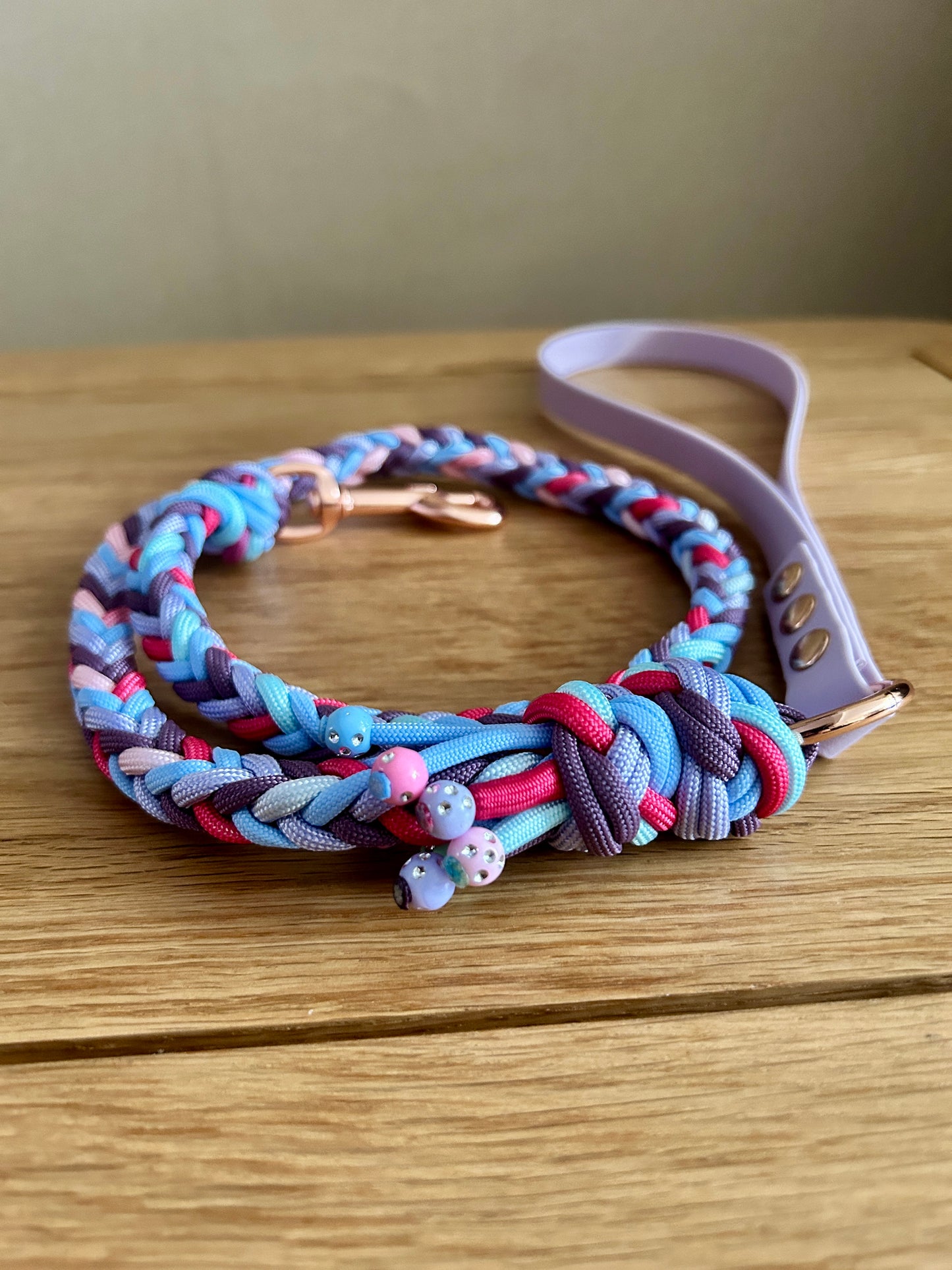 Colorful braided dog leash on a wooden surface with a neutral background