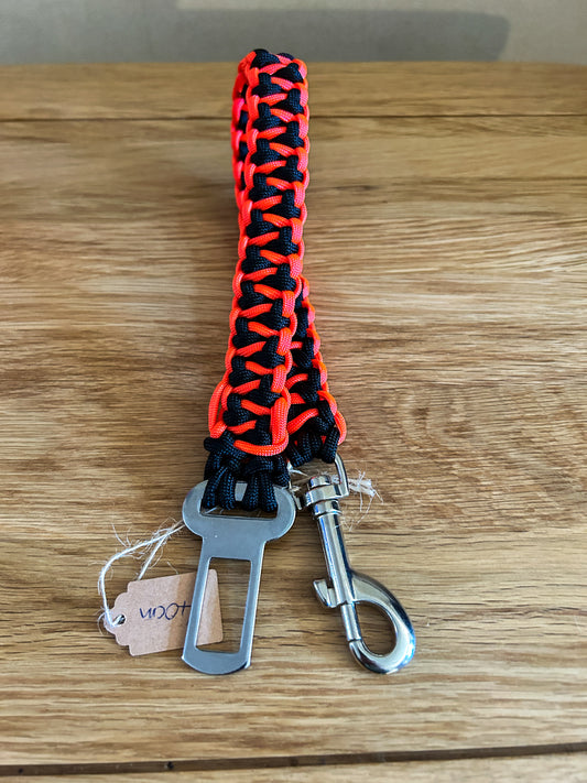 Paracord seatbelt safety clip for dogs in a black and neon orange pattern on a wooden background