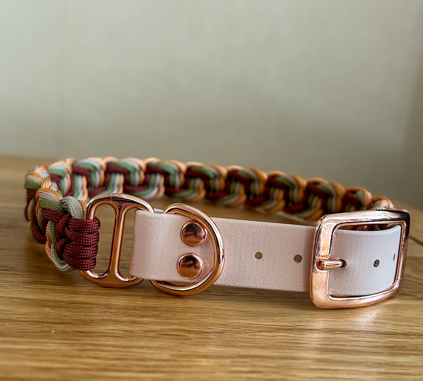 Dog collar with braided design and rose gold hardware on a wooden surface