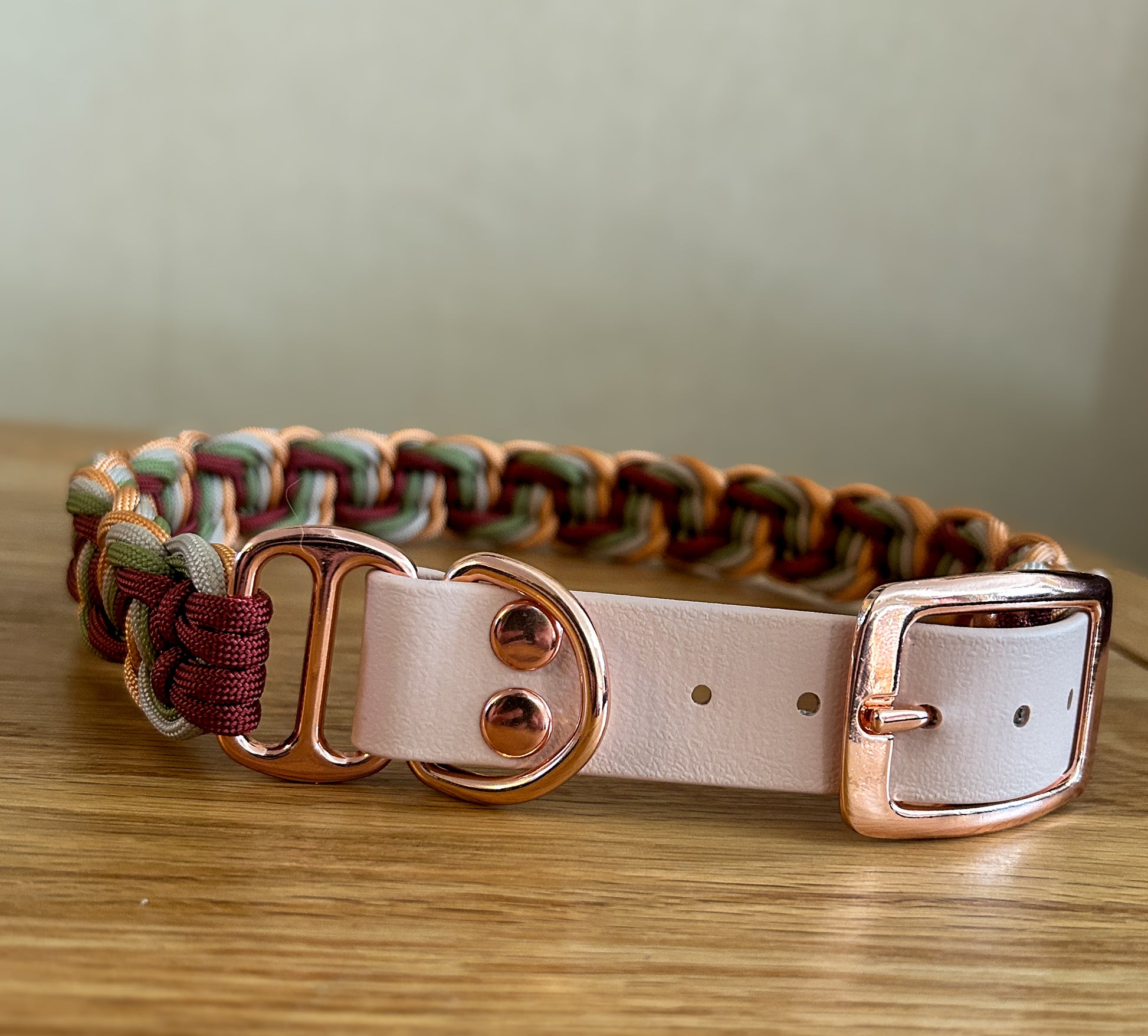 Dog collar with braided design and rose gold hardware on a wooden surface