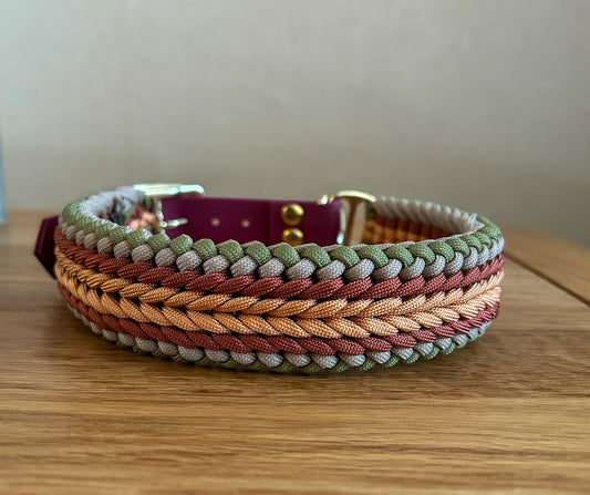 Multicolored braided dog collar on a wooden surface with a neutral background