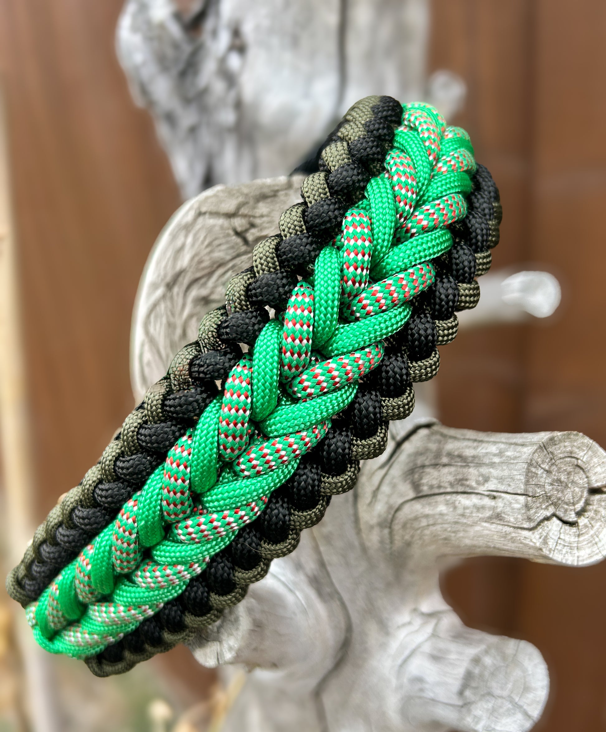 braided paracord collar in greens and black on a tree stump