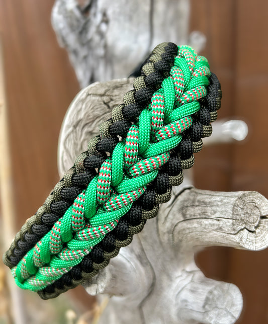 braided paracord collar in greens and black on a tree stump