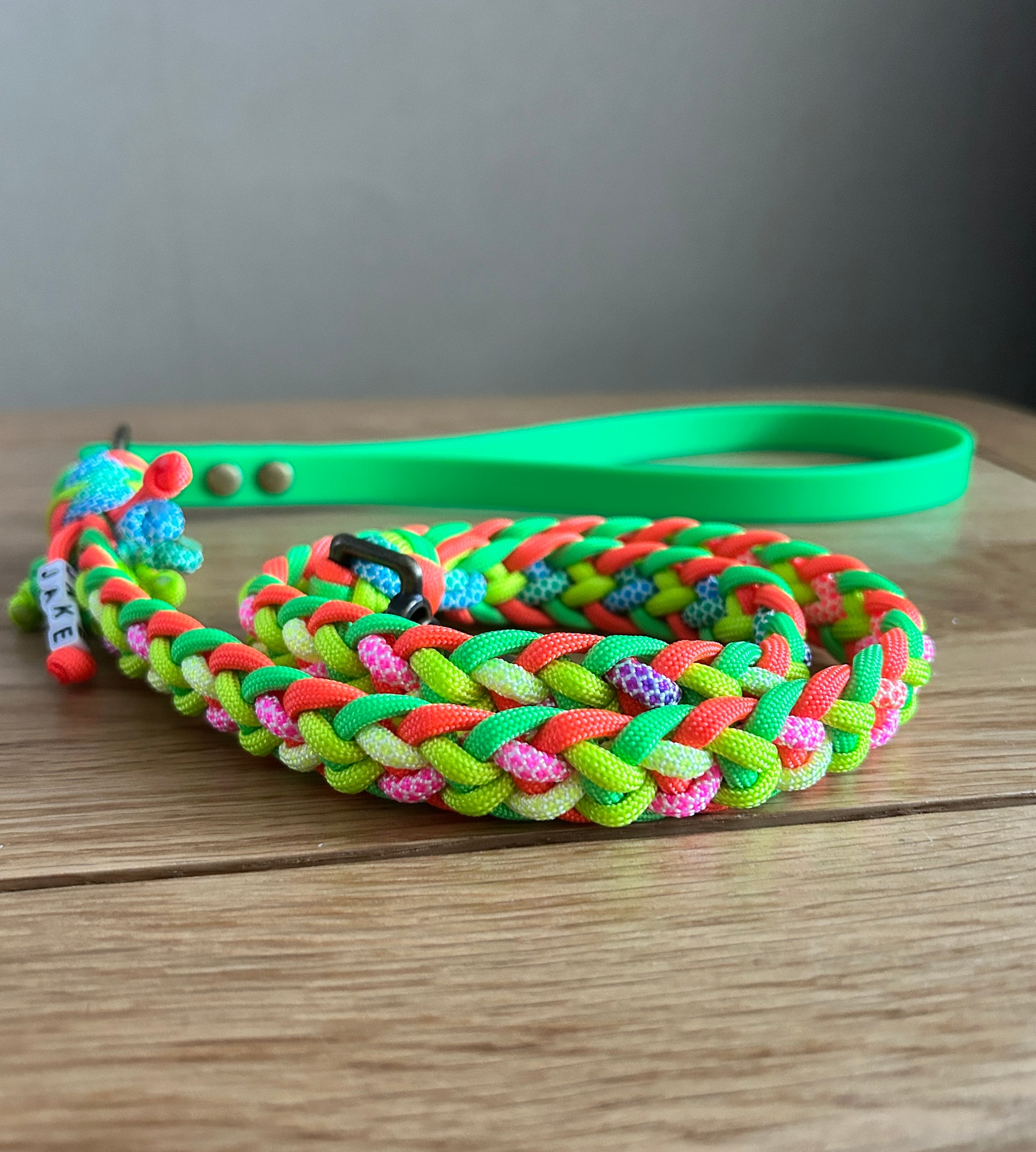 Colorful braided dog leash on a wooden surface with a neutral background