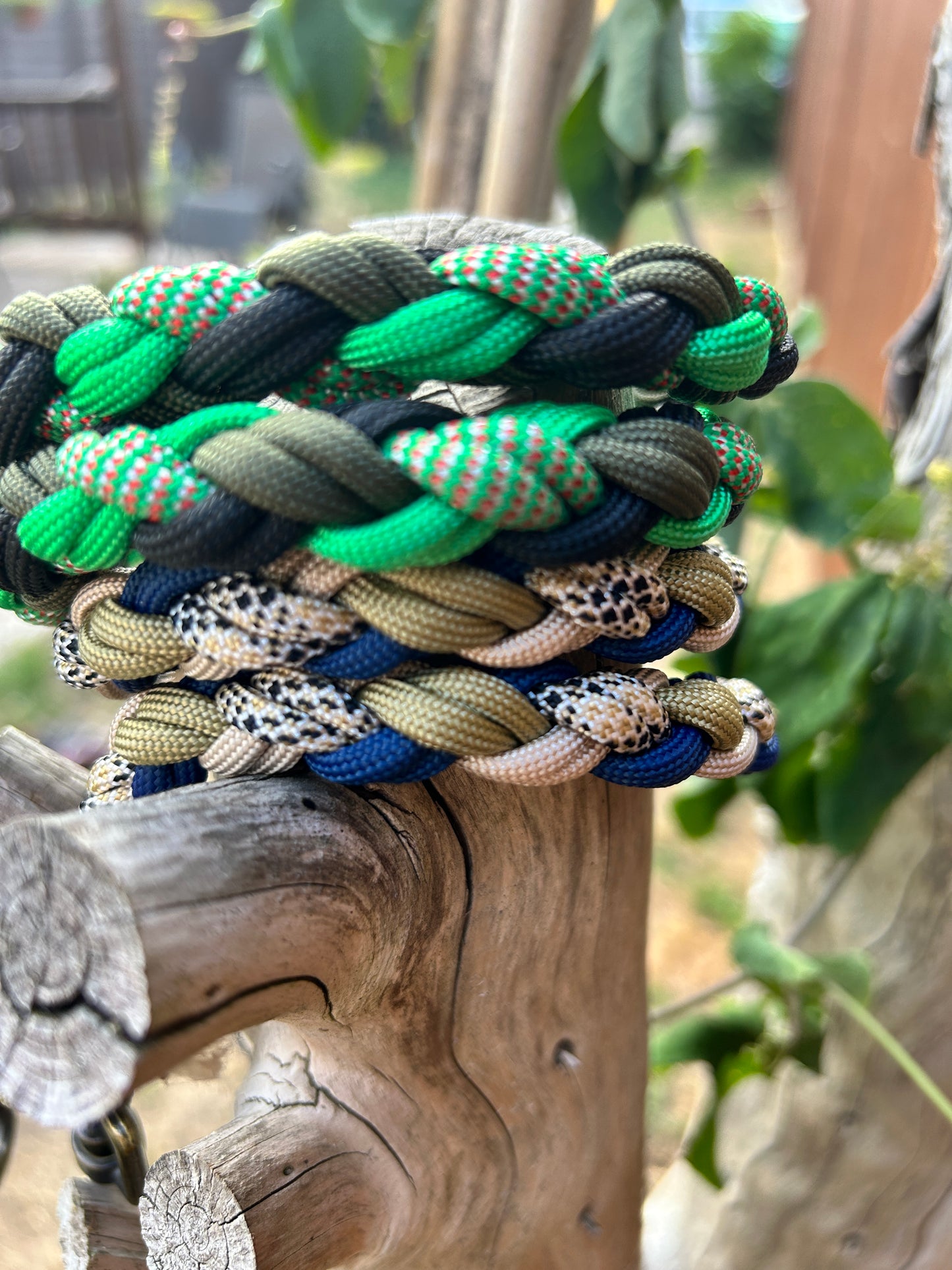Colourful braided paracord leads on a wooden surface with blurred greenery in the background