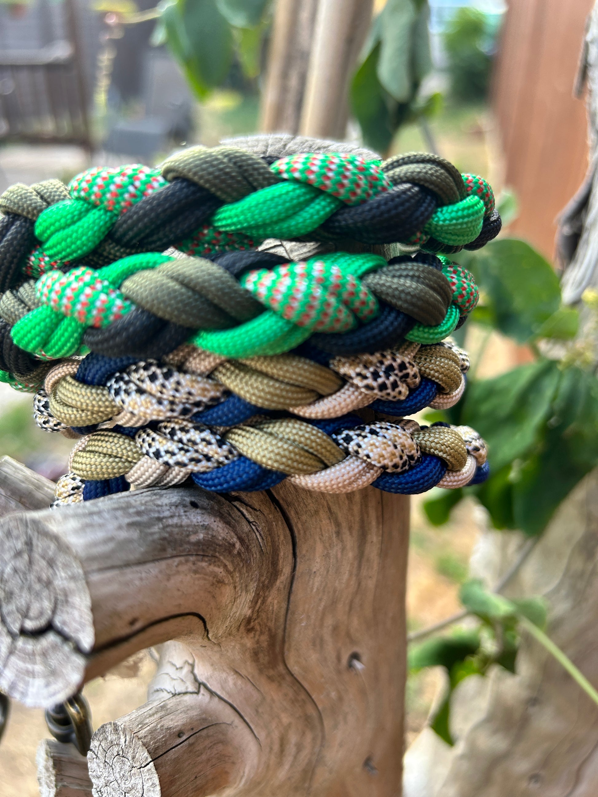 Colourful braided paracord leads on a wooden surface with blurred greenery in the background