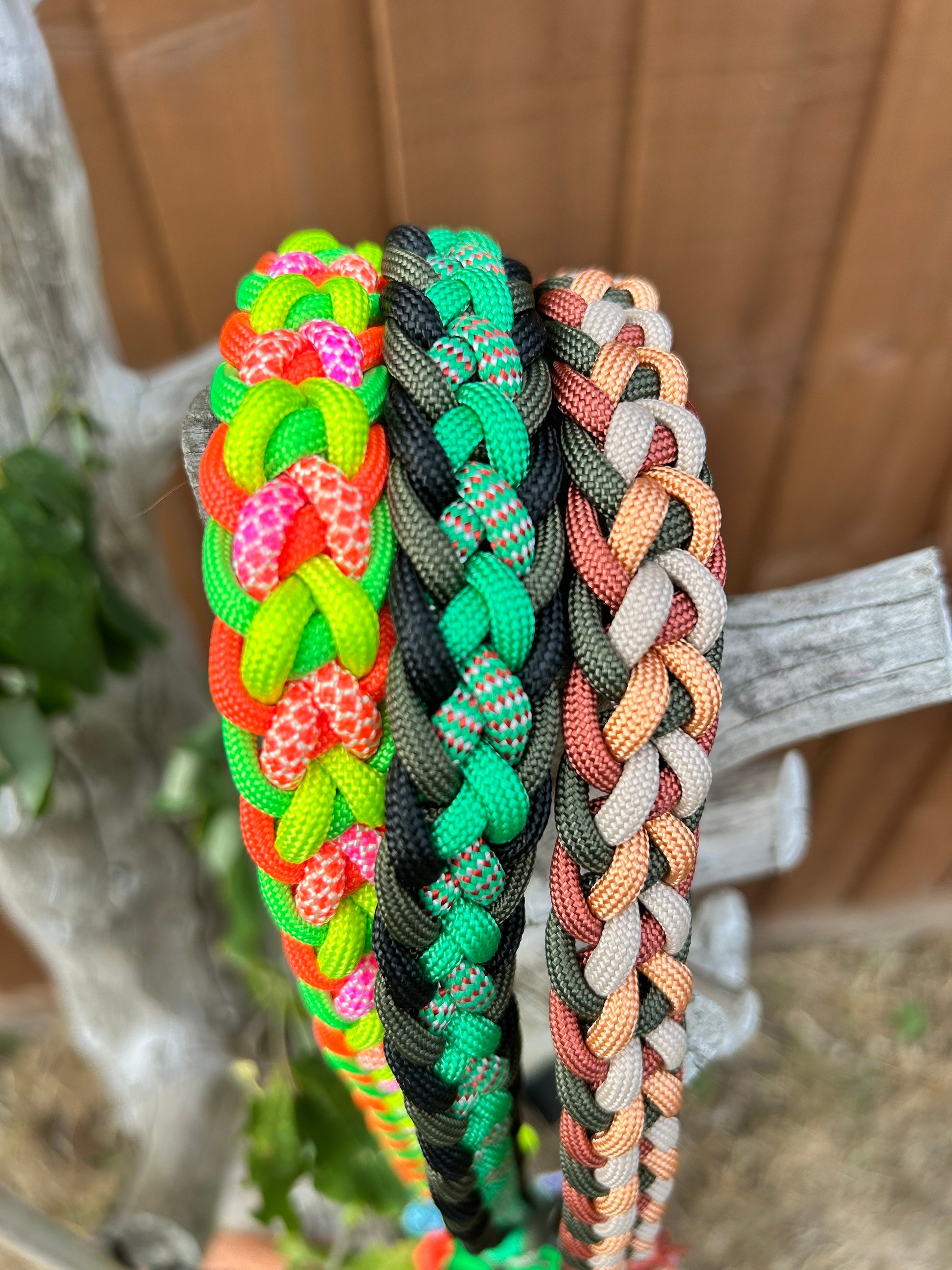 three braided paracord leads in different colours on a wooden stand